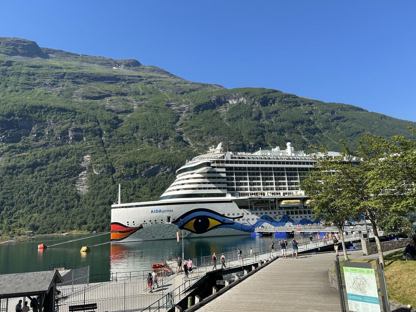 Eigene Aufnahme der AIDAprima am Kai im Geirangerfjord, im Hintergrund ein bewaldeter Berg