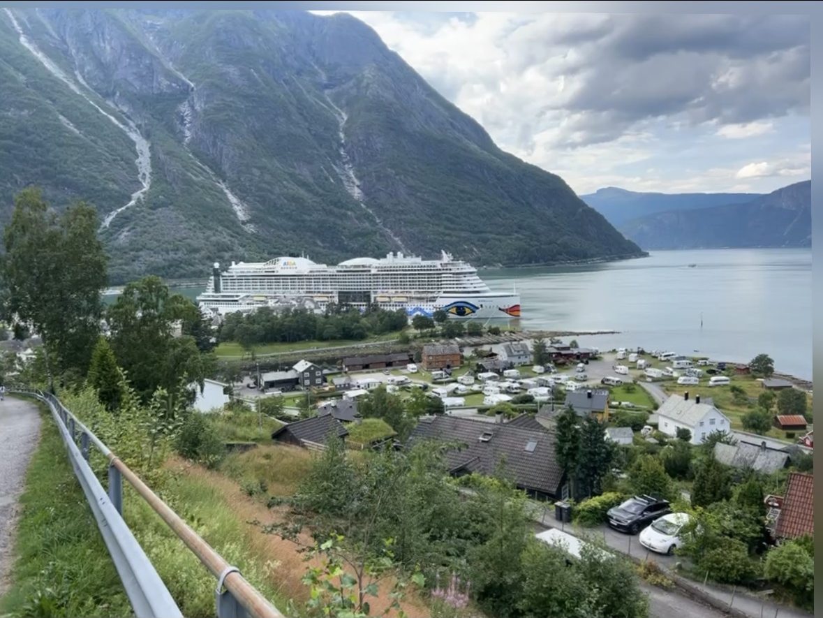 Kreuzfahrtschiff im Eidfjord, umgeben von steilen Berghängen mit Wasserfällen, Norwegen