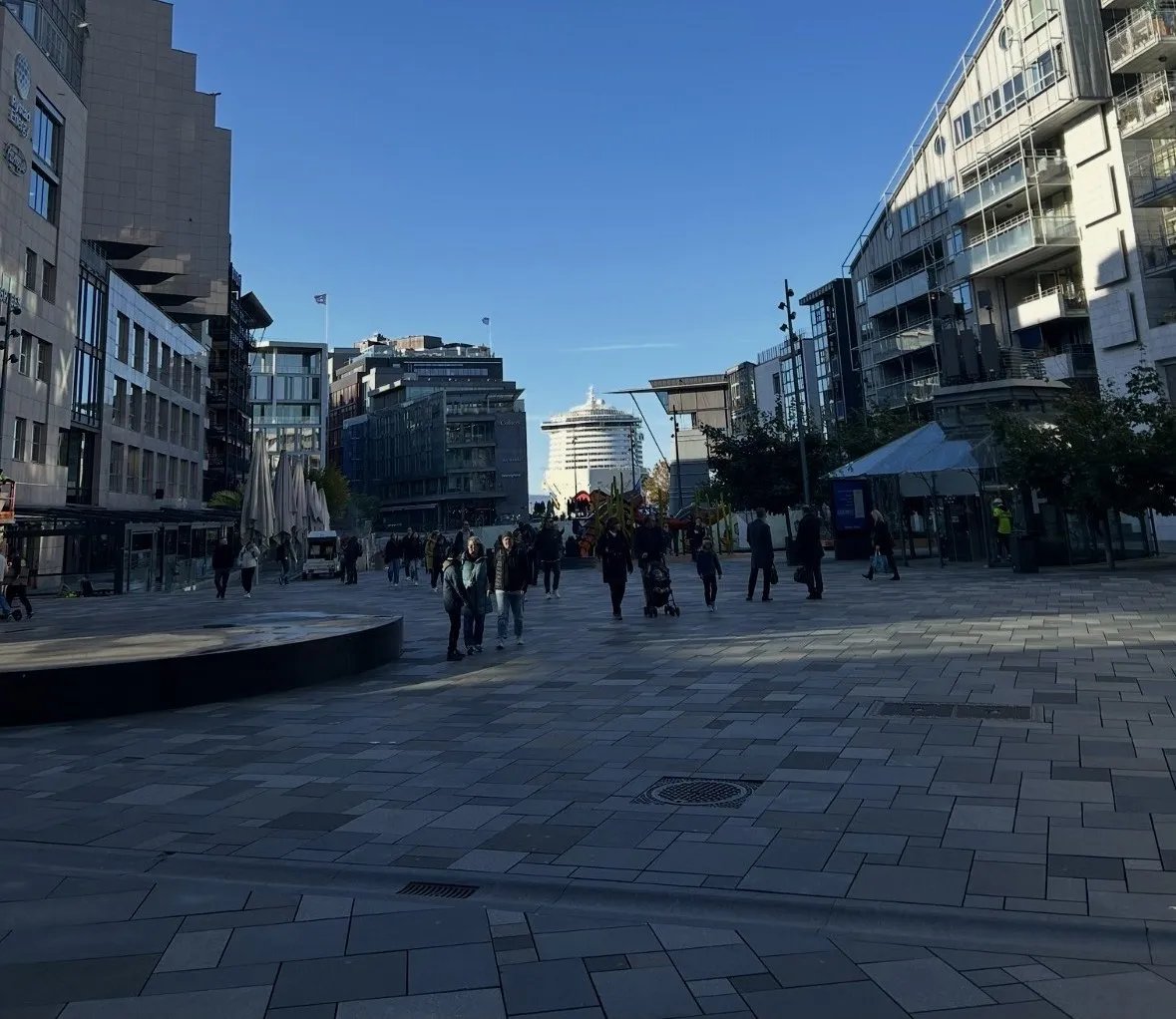 Fußgängerzone in Aker Brygge, Oslo, mit Kreuzfahrtschiff im Hintergrund