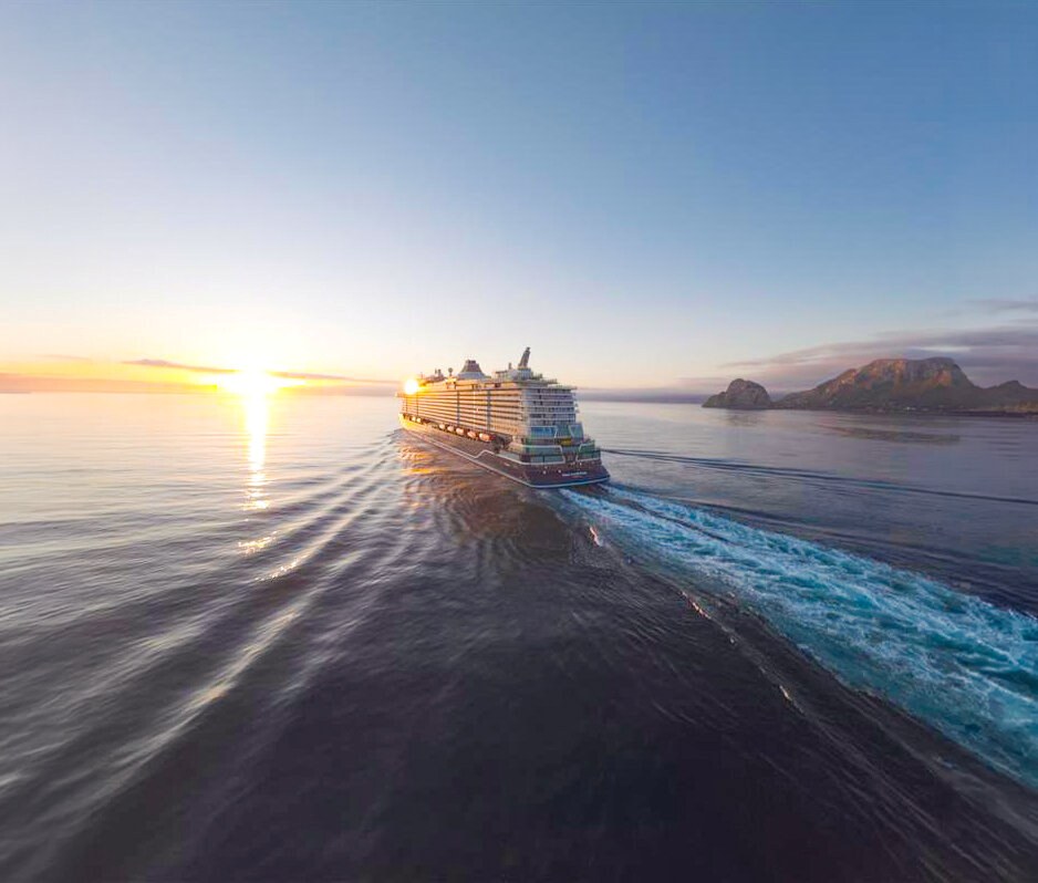 Pressefoto von TUI Cruises, ein Mein-Schiff-Neubau fährt bei Sonnenuntergang aufs offene Meer
